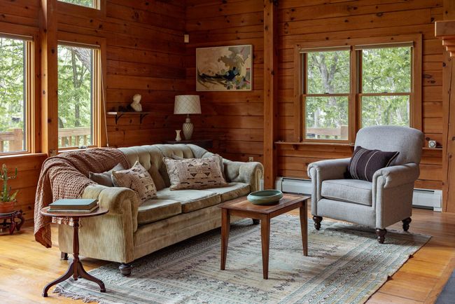 Living room with a baseboard heating unit, wood walls, and wood finished floors | Image 11