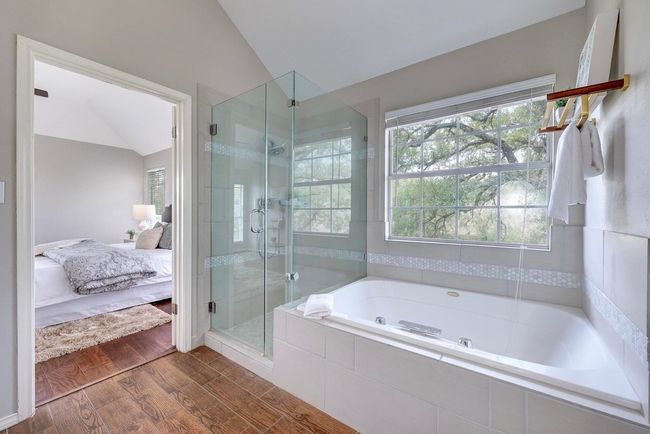 Full bath featuring connected bathroom, vaulted ceiling, a shower stall, a garden tub, and wood finished floors | Image 24