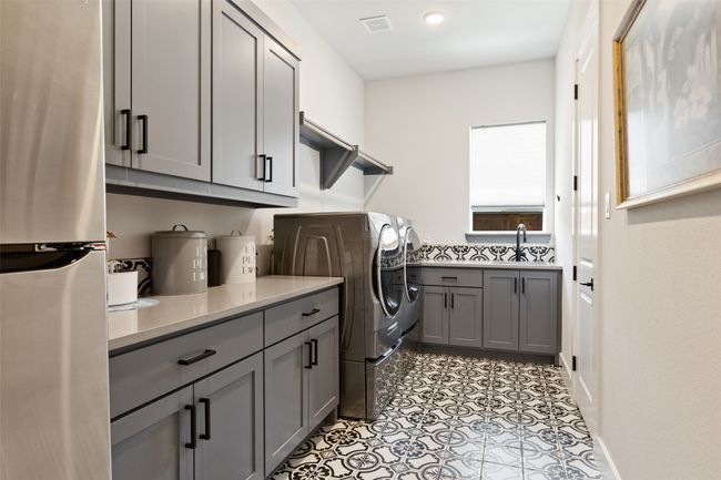 Laundry area with light tile patterned floors, visible vents, cabinet space, a sink, and independent washer and dryer | Image 22