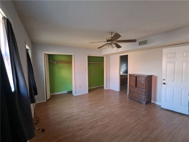 Unfurnished bedroom featuring multiple closets, wood finished floors, and ceiling fan | Image 10
