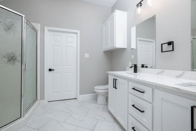 Full bathroom with marble look tiles, a shower stall, and double vanity | Image 30