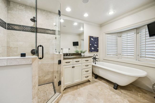 Primary bathroom with free standing tub, frameless shower and dual vanities. | Image 13