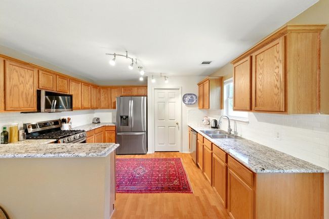 Kitchen with stainless steel appliances, a sink, light wood-style floors, and backsplash | Image 17