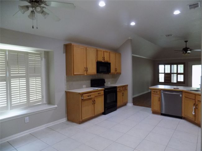 Kitchen featuring black appliances, a ceiling fan, vaulted ceiling, decorative backsplash, and recessed lighting | Image 17