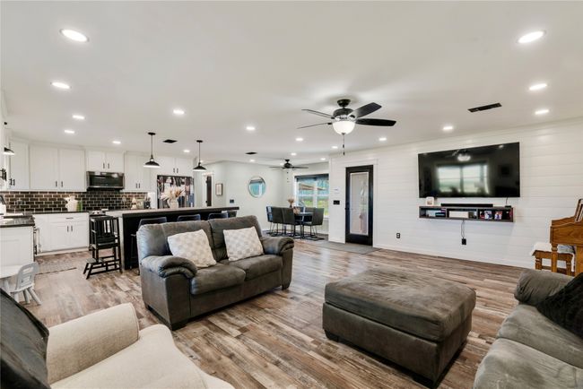 Living area featuring recessed lighting, light wood-type flooring, baseboards, visible vents, and a ceiling fan | Image 5