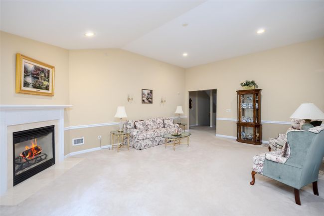 Living area with vaulted ceiling, a fireplace with flush hearth, carpet flooring, and recessed lighting | Image 12