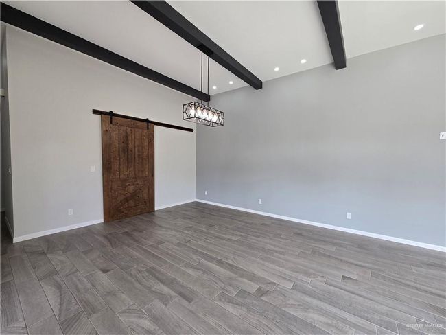 Spare room with beam ceiling, a barn door, baseboards, and recessed lighting | Image 6