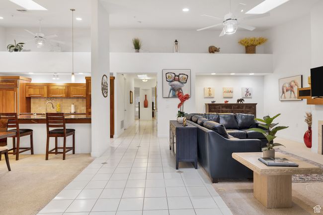Living room featuring recessed lighting, light tile patterned flooring, a towering ceiling, and ceiling fan | Image 10