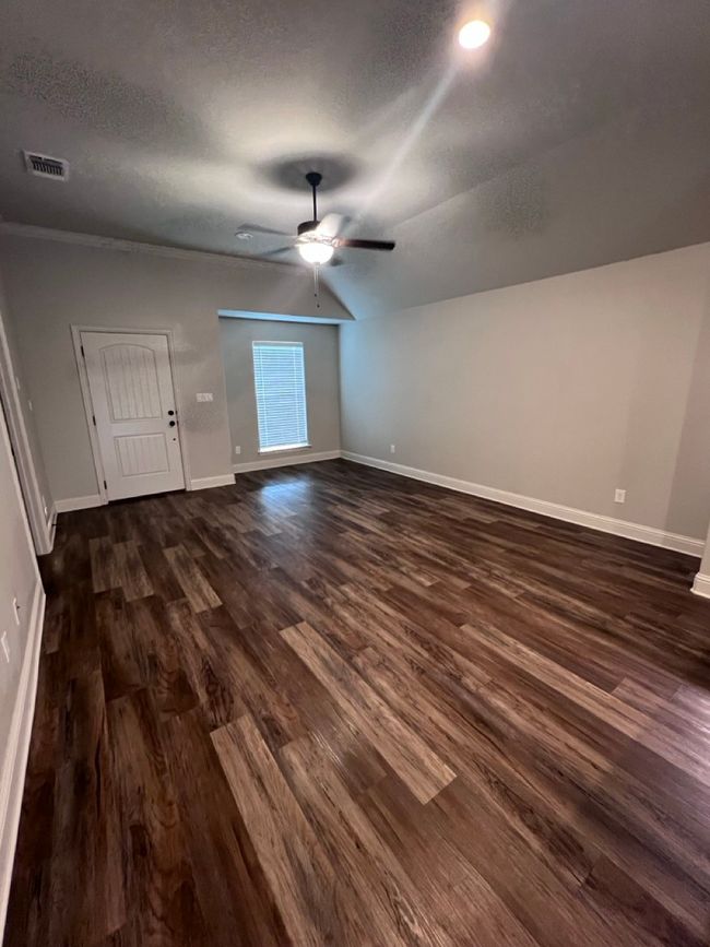 Unfurnished living room with dark wood-type flooring, a ceiling fan, baseboards, a textured ceiling, and lofted ceiling | Image 40