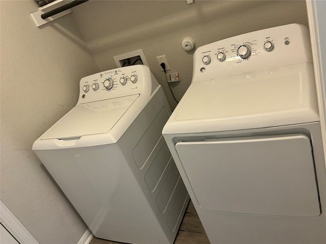 Washroom featuring independent washer and dryer, a textured wall, and wood finished floors | Image 10
