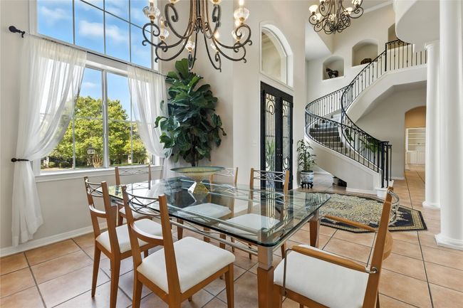 Tiled dining room featuring a chandelier, a high ceiling, stairway, and arched walkways | Image 10