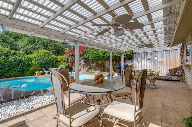 Fenced backyard featuring a ceiling fan, a pergola, outdoor dining area, and a patio area | Image 24