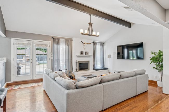 Vaulted ceiling, hardwood flooring, double doors to the patio, updated lighting, and a wall with fireplace and windows to the backyard! | Image 4