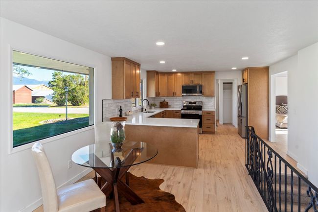 Kitchen featuring decorative backsplash, light hardwood / wood-style flooring, sink, stainless steel appliances, and kitchen peninsula | Image 14