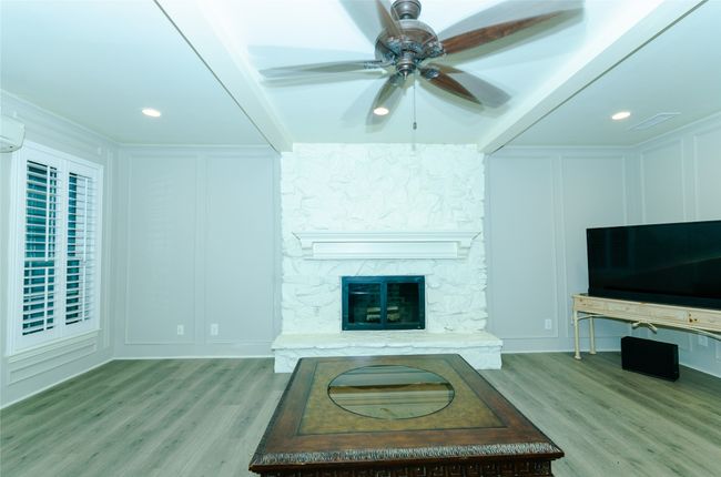 Living area with a decorative wall, a ceiling fan, a stone fireplace, recessed lighting, and light wood finished floors | Image 5