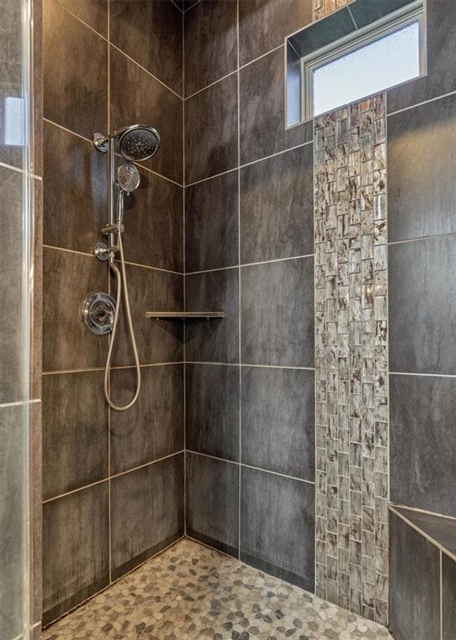 A closer look at the shower reveals thoughtful design elements, including a built-in bench seat, convenient storage shelf, and a striking glass tile accent. | Image 33