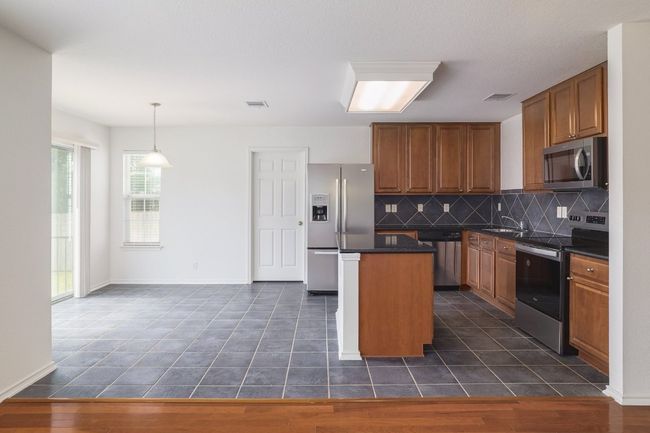 Kitchen featuring a sink, stainless steel appliances, decorative backsplash, visible vents, and dark countertops | Image 11