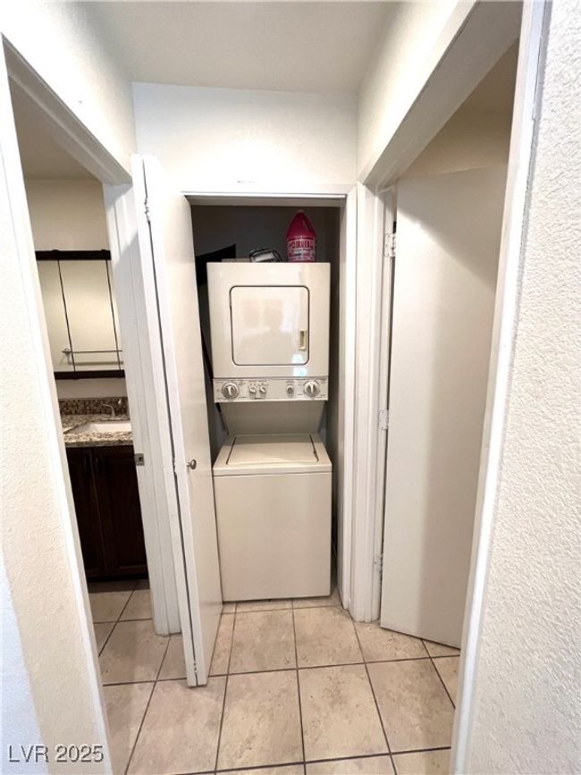 Clothes washing area with stacked washer / drying machine, laundry area, and light tile patterned floors | Image 9