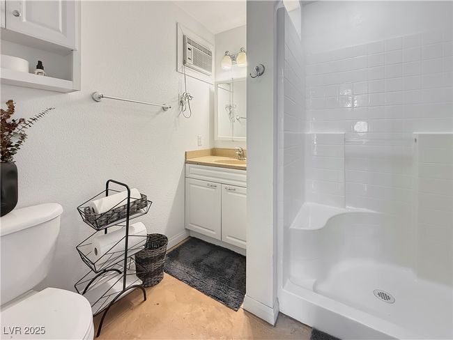 Bathroom with toilet, vanity, walk in shower, and a textured wall | Image 40