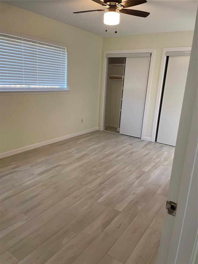 Unfurnished bedroom featuring multiple closets, baseboards, light wood-type flooring, and a ceiling fan | Image 10
