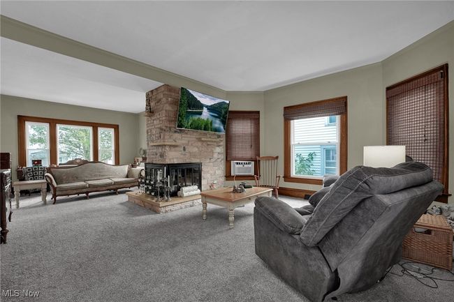 Living area with a fireplace and carpet flooring. | Image 6