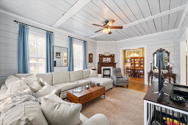 Living area featuring wood walls, wood ceiling, light wood-style floors, a ceiling fan, and crown molding | Image 9