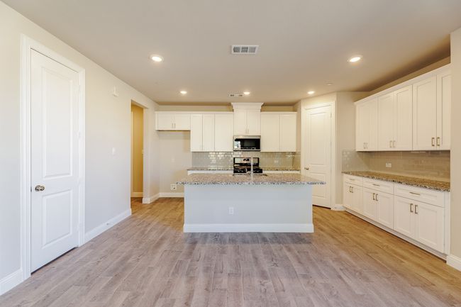 Kitchen with stainless steel microwave, range, backsplash, white cabinets, and recessed lighting | Image 10
