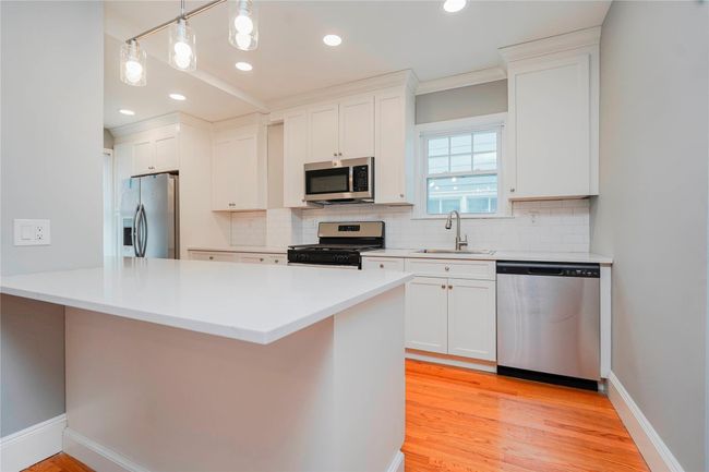 Kitchen with stainless steel appliances, white cabinets, a sink, and backsplash | Image 11
