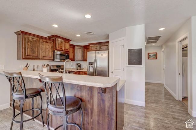 Kitchen featuring a breakfast bar, light countertops, baseboards, appliances with stainless steel finishes, and visible vents | Image 5