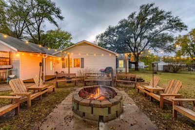 Back of house with an outdoor fire pit, a storage unit, a yard, and a patio area | Image 3