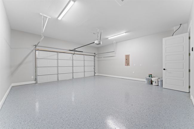 Garage with baseboards, a garage door opener, and electric panel | Image 26
