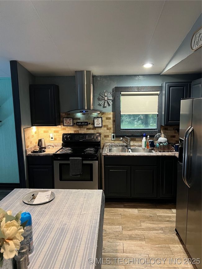 Kitchen featuring range, fridge, exhaust hood, a sink, and decorative backsplash | Image 10