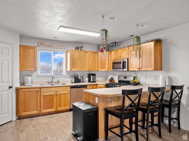 Kitchen with a breakfast bar, sink, light hardwood / wood-style flooring, appliances with stainless steel finishes, and kitchen peninsula | Image 8