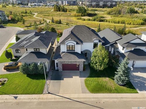White stucco exterior, stone facade accents, dark asphalt shingle roofing, attached garage with a red door, concrete driveway | Card Image