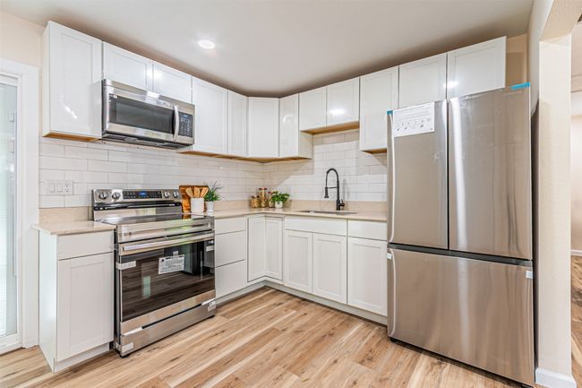 Kitchen with light countertops, a sink, appliances with stainless steel finishes, and light wood-style flooring | Image 9