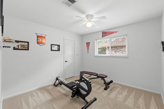 This room features neutral walls and carpet, with a ceiling fan and a window providing natural light. | Image 25