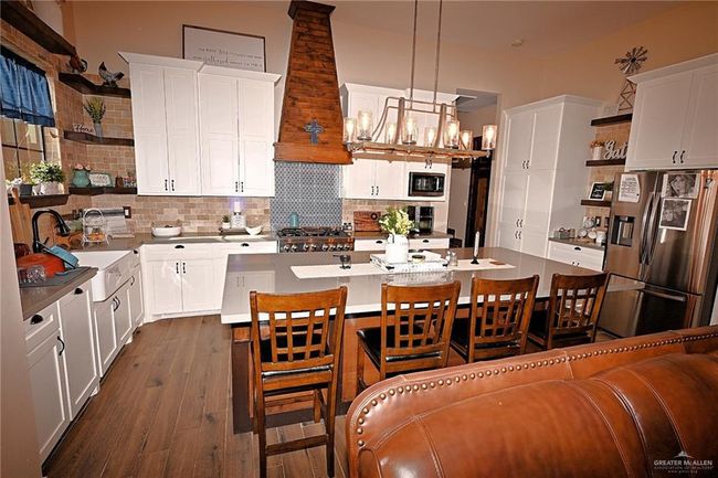 Kitchen featuring backsplash, stainless steel appliances, white cabinets, dark wood-type flooring, and custom exhaust hood | Image 11
