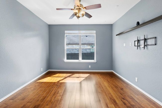 Spare room with a textured wall, wood finished floors, and ceiling fan | Image 7