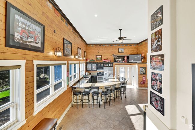 Dining space with ornamental molding, wooden walls, ceiling fan, and a wealth of natural light | Image 42