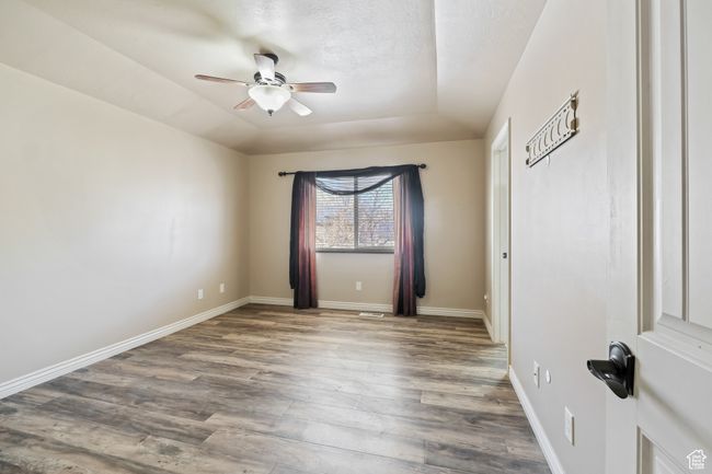 Unfurnished room with wood finished floors, ceiling fan, a tray ceiling, and baseboards | Image 10