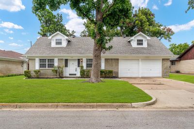 Cape cod-style house featuring a garage and a front yard | Image 1