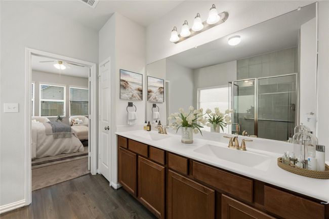 This primary bathroom is definitely move-in ready! Featuring a dark framed walk-in shower with tile surround, separate garden tub for soaking after a long day with custom tile detailing, dark stained cabinets with light countertops, spacious walk-in closet with shelving, high ceilings, custom paint, and sleek finishes. *Virtually Staged | Image 14