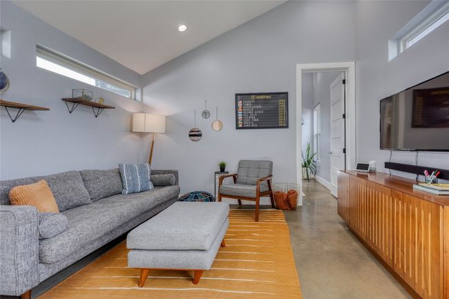 Living room with finished concrete flooring, high vaulted ceiling, recessed lighting, and baseboards | Image 6