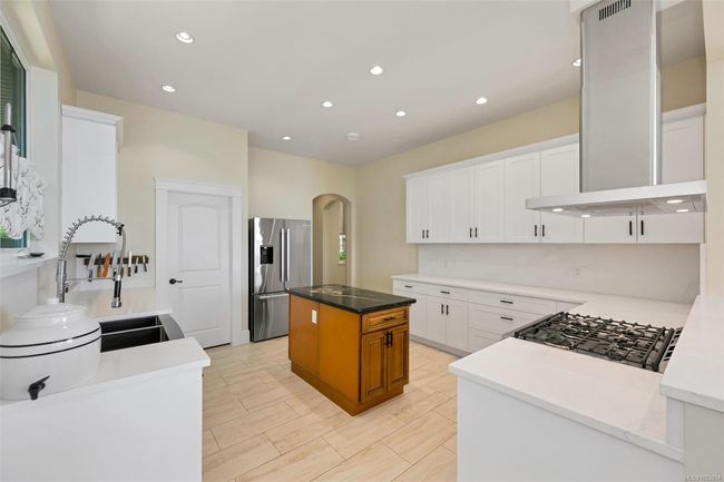 Kitchen with appliances with stainless steel finishes, wall chimney exhaust hood, arched walkways, white cabinetry, and recessed lighting | Image 49