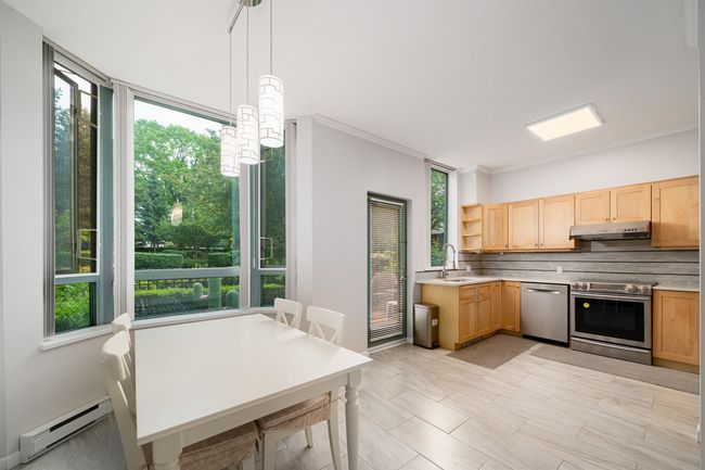 Kitchen featuring stainless steel appliances, a baseboard radiator, under cabinet range hood, open shelves, and light brown cabinetry | Image 9