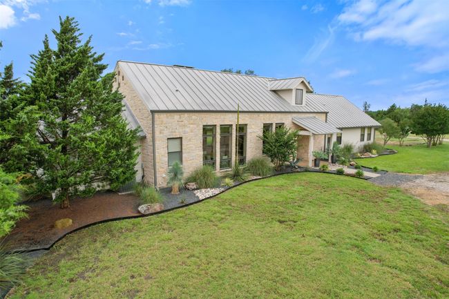 View of front of property featuring a standing seam roof, stone siding, a front lawn, and a metal roof | Image 8