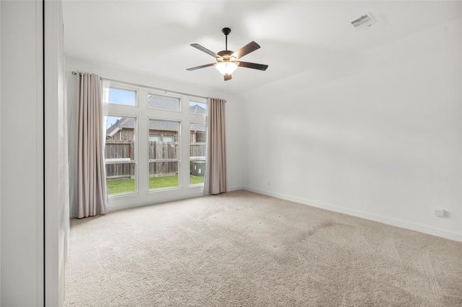 Bright and airy primary bedroom provides a comfortable living space with plenty of natural light. | Image 15