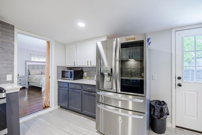 Kitchen featuring tasteful backsplash, light countertops, white cabinetry, and appliances with stainless steel finishes | Image 12
