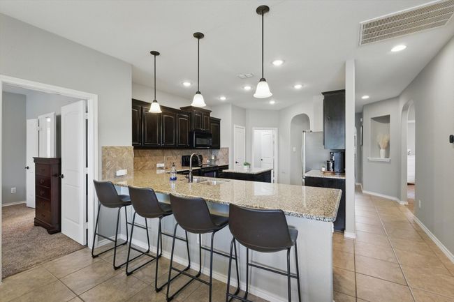 Kitchen with arched walkways, visible vents, a sink, and black appliances | Image 10