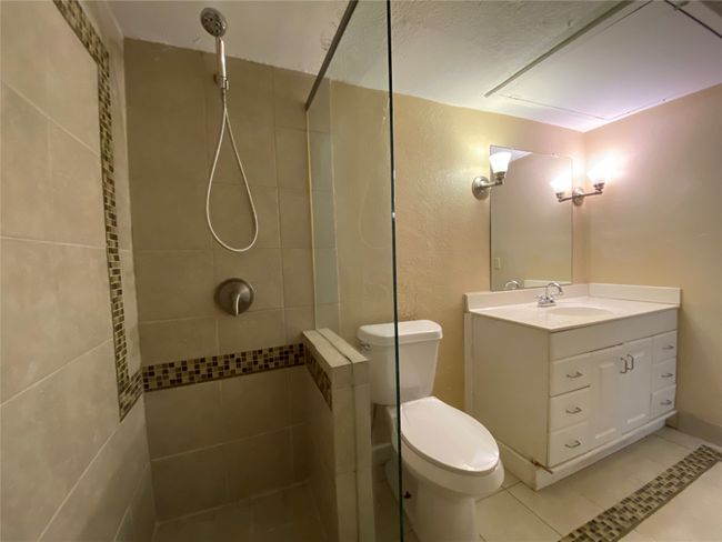 Bathroom featuring toilet, vanity, tile patterned flooring, and tiled shower | Image 14
